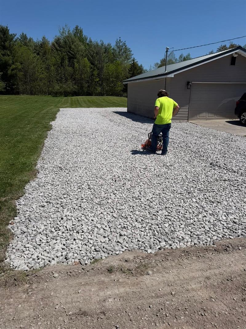 Compacting a fresh gravel driveway beside a garage