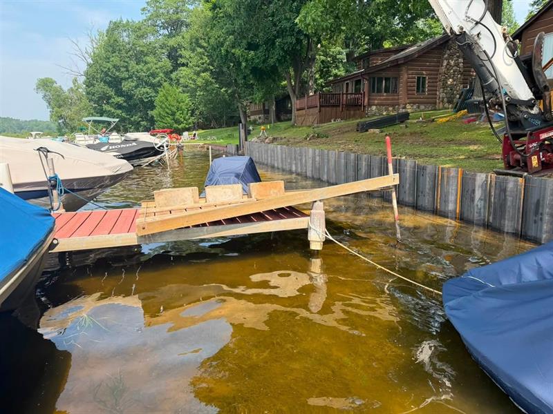 New steel seawall protecting a lakefront lawn, with dock and boats